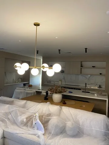 Brass globe pendant suspended over a marble kitchen island with the joinery still sheeted for handover