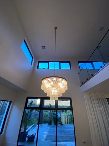 Crystal drum chandelier in a double height void with dusk light through the clerestory windows