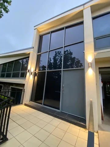 Vertical up and down light on a render pier beside a glazed facade at dusk