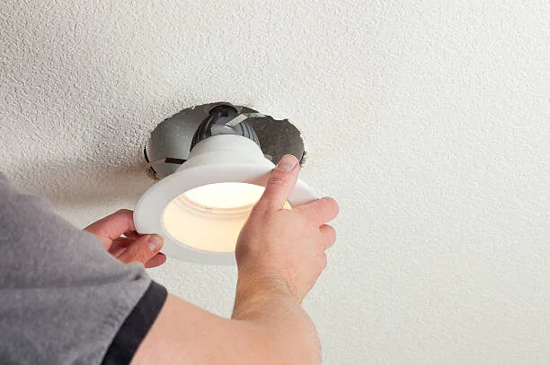 Hand pushing a warm LED downlight up into a ceiling cutout