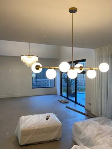 Brass globe pendant and a ribbed glass fitting lighting an open plan living room before handover