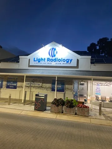 Illuminated Light Radiology shopfront sign glowing above the glazed frontage at dusk