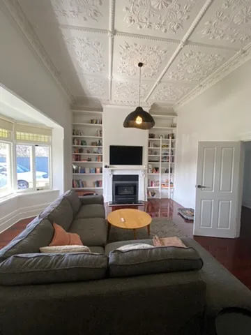 Black dome pendant hanging below the pressed tin ceiling of a restored Adelaide villa lounge